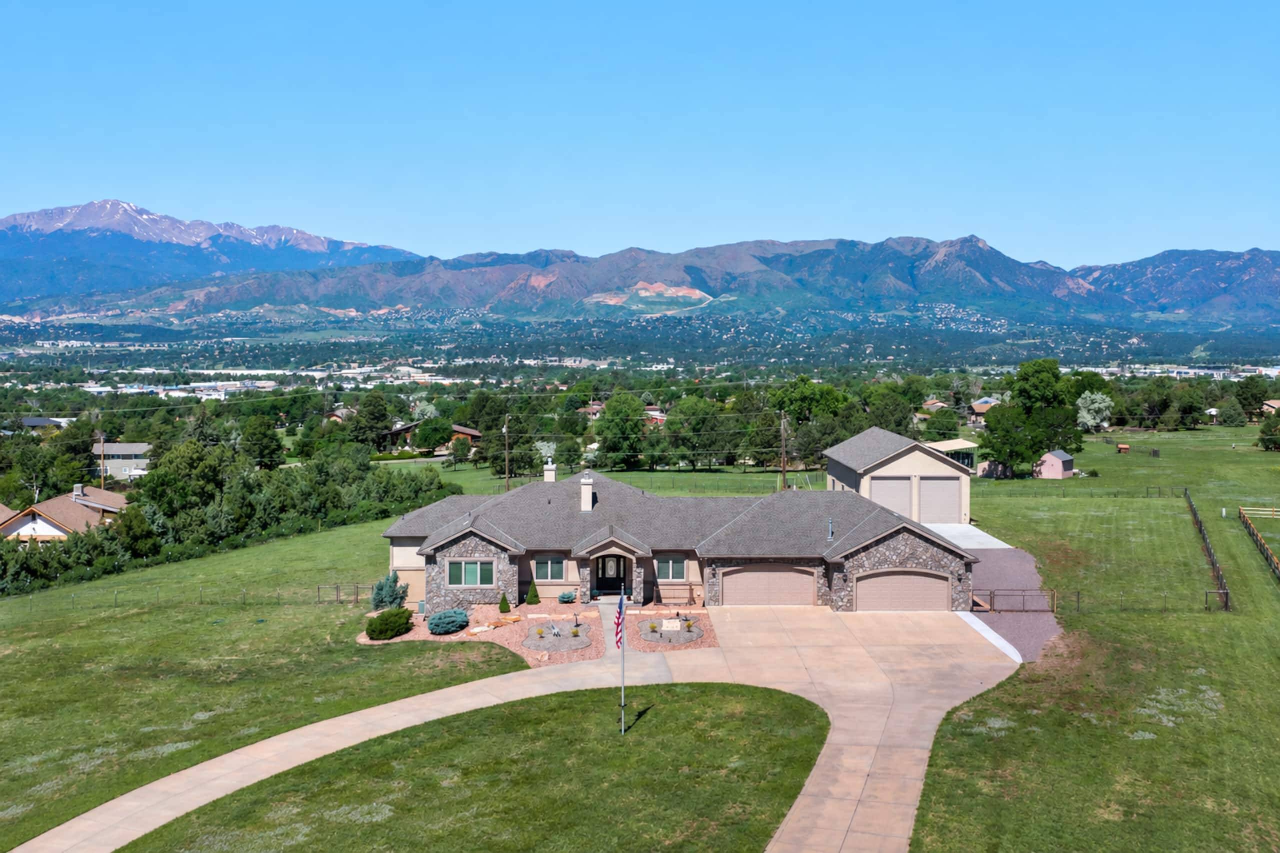 Aerial view of the house on its open acreage with the Front Range and Pikes Peak behind