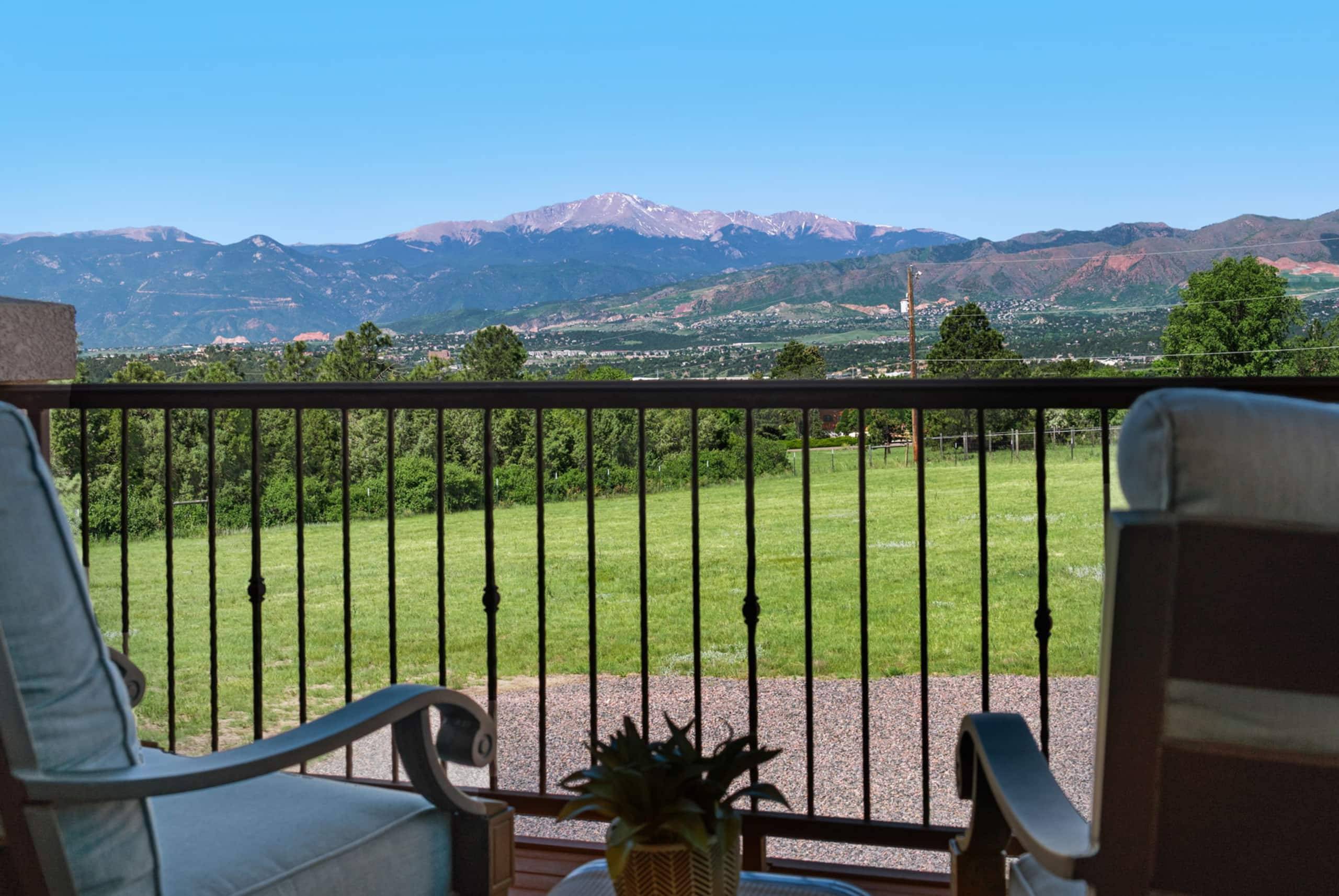The view from the deck: a green lawn falling away to the Front Range and Pikes Peak under a clear sky