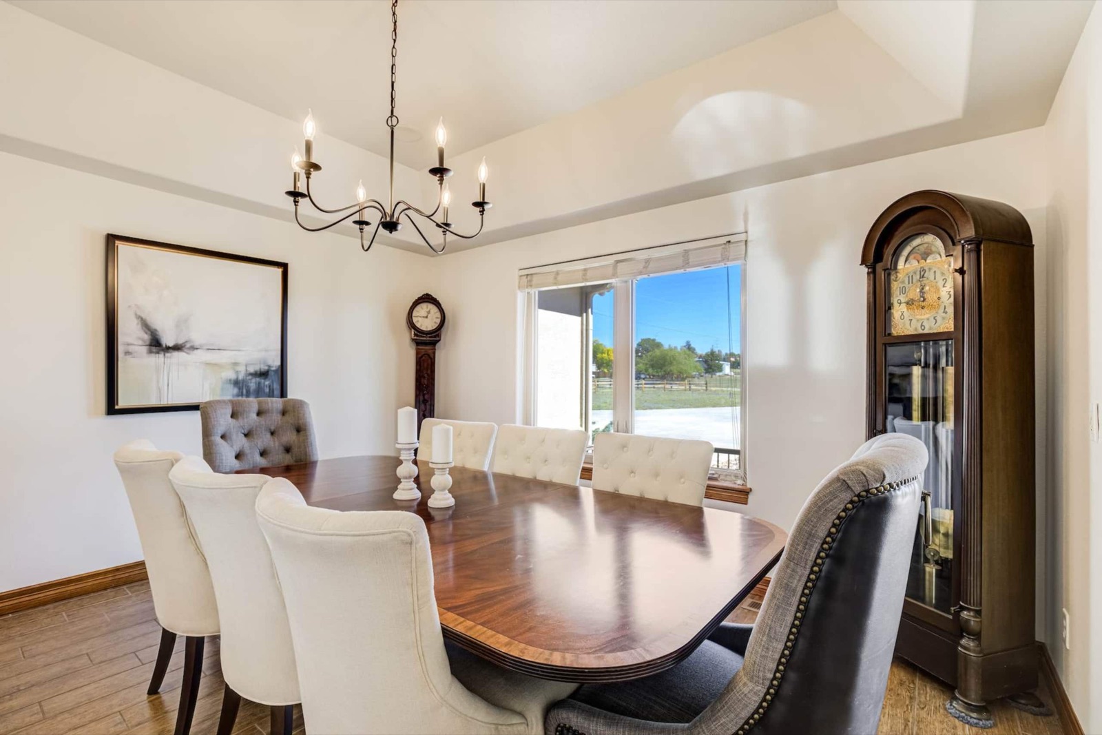 Formal dining room with the table extended and eight upholstered chairs under a candle chandelier
