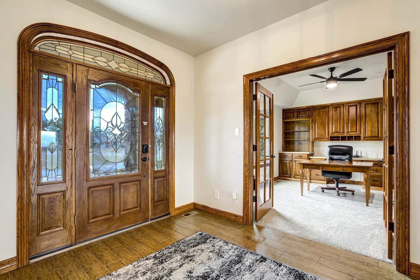 The arched wooden double front doors with leaded glass, opening onto the entry hall