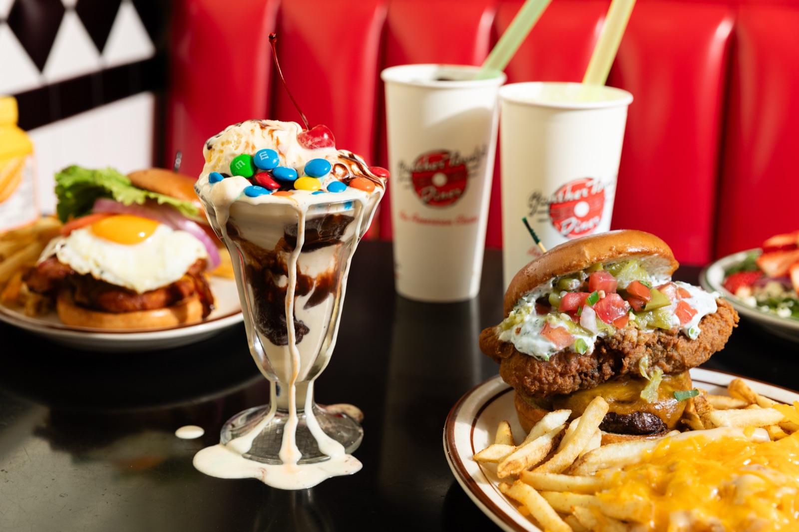 A Gunther Toody's booth with a burger, cheese fries and a sundae under red diner seats