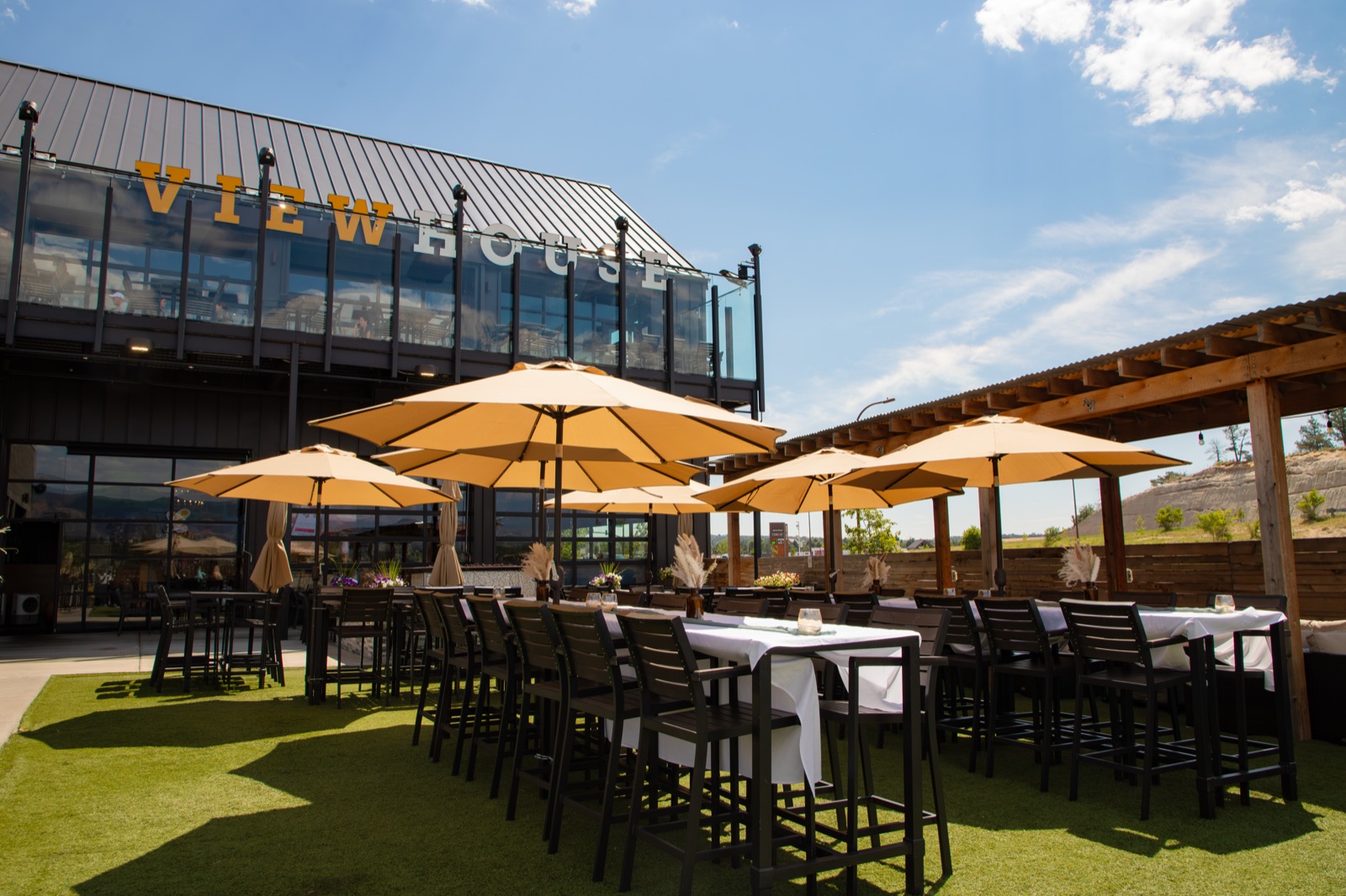 The View House patio in Colorado Springs, with umbrellas, white tablecloths and the rooftop deck above